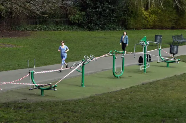 A runner runs past a closed playground in Glasgow