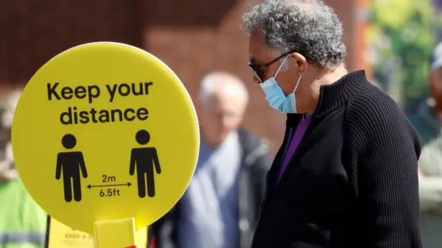 A man wearing a protective face mask queues at a B ^ Q store in Liverpool, following the outbreak of the coronavirus disease