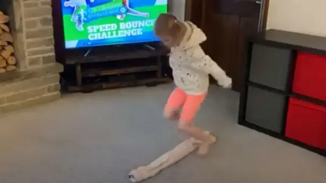 A girl jumps over a towel