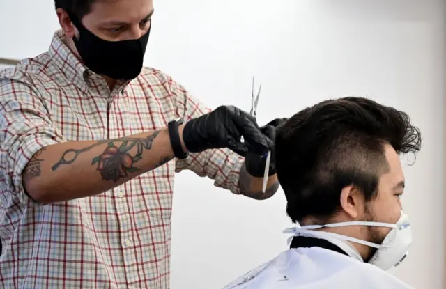 A hairdresser wearing a mask cuts hair of his masked client in Kyiv, Ukraine. Photo: 11 May 2020