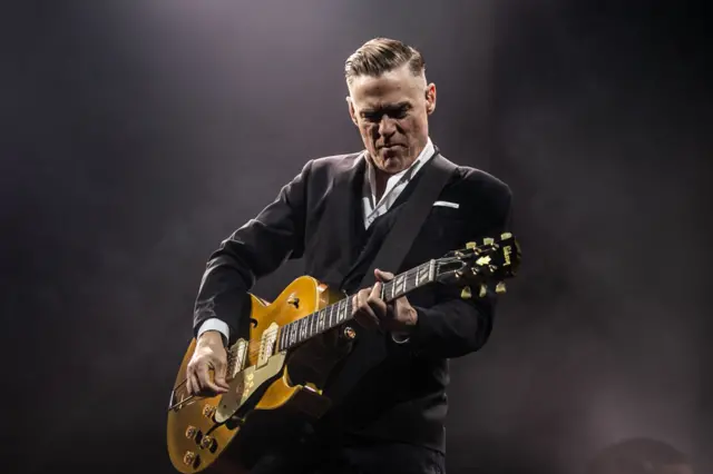 Bryan Adams playing on stage at a concert in the UK last year