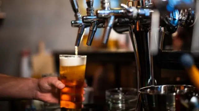 A pint of beer being poured in a bar