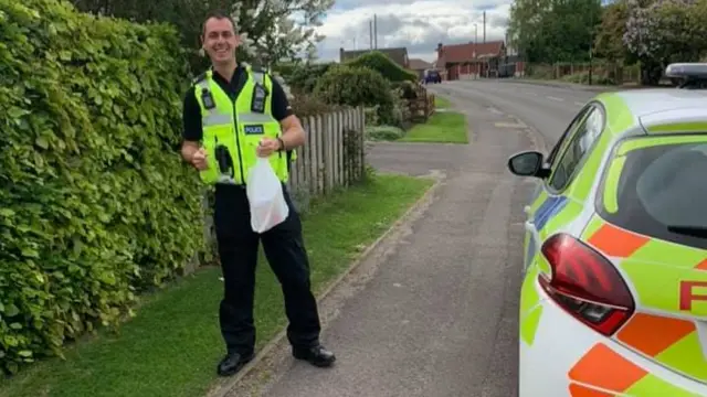 Police officer holding a bag of food