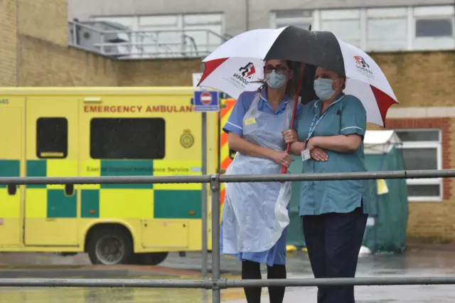 nurses standing in the pouring rain during the silence honouring key workers