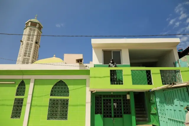 A man wears a face mask as he stands on a balcony of a closed mosque in Dakar, Senegal