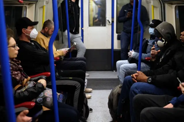 Commuters sitting next to each other on a tube