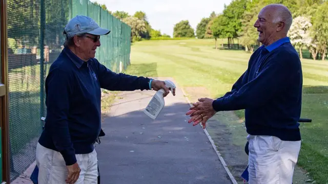 At Filton Golf Club, two golfers spray their hands before heading out on to the course.