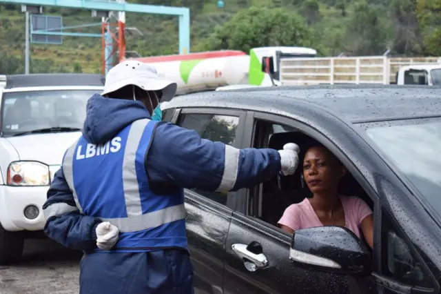 A Lesotho health official measures temperatures of motorists as a preventive measure against the spread of the COVID-19 coronavirus at the Maseru bridge in in Maseru, Lesotho, on March 10, 2020