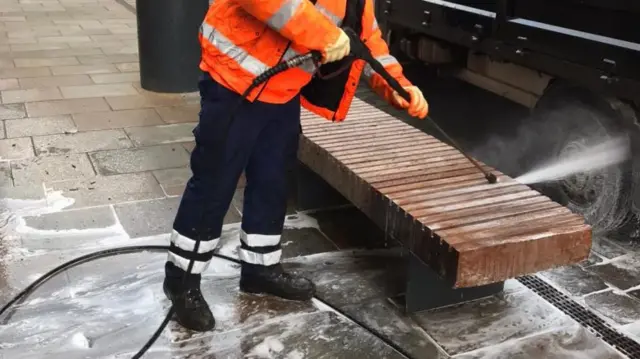 A worker cleans a bench