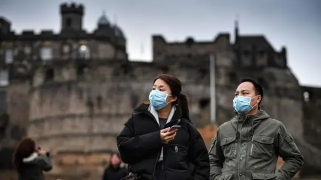 Edinburgh Castle with folk wearing masks in the foreground