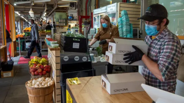 Two people prepare orders in a market