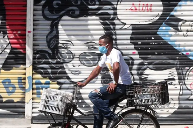 A person with a mask rides a bicycle, during the quarantine decreed by the Governor of Sao Paulo Joao Doria, to stop the spread of coronavirus, through the downtown area of Sao Paulo, Brazil, 13 April 2020.