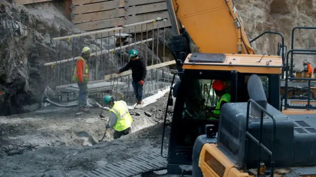 Construction workers in a pit with a crane