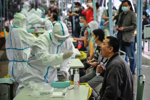 A medical worker takes a swab sample from a resident to be tested for the COVID-19 coronavirus in Wuhan