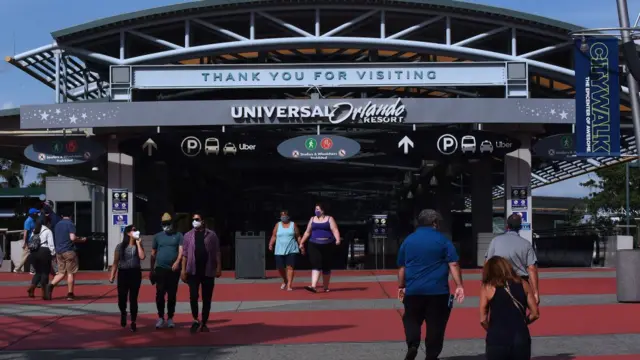 People wearing face masks walking at the entrance to Universal Orlando Resort