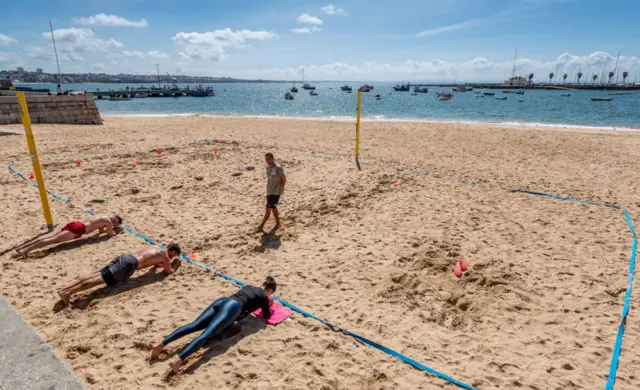 People exercise on Cascais beach near Lisbon