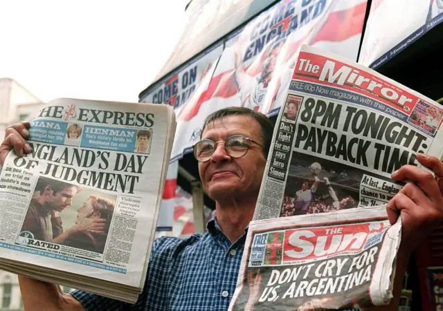 Man holds up newspapers on day of game