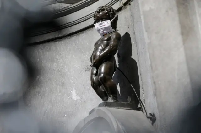 Manneken Pis fountain sculpture wearing a face mask