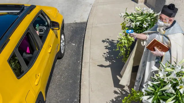 A priest fires water from a water pistol into a nearby car