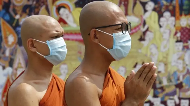 Two monks wearing face masks