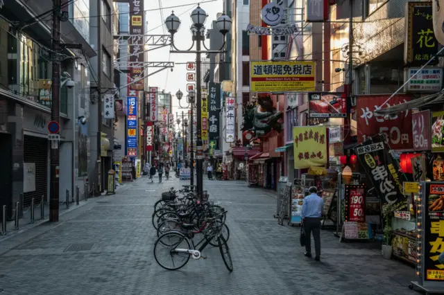 A man walks past mostly closed shops in Dotonbori,