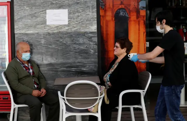 People sitting at a table get served at a cafe, as most Spanish provinces are allowed to ease restrictions during phase one, amid the coronavirus disease outbreak, in Ronda, Spain, 18 May