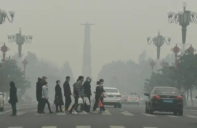 People wearing face masks walk in smog on April 15, 2020 in Changchun, Jilin Province of China