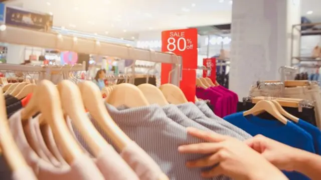 A shopper browsing through a rail of clothes