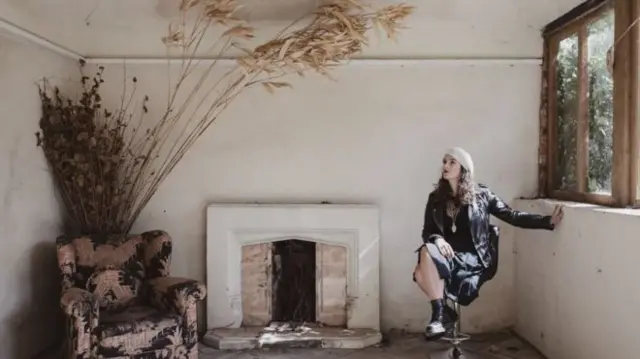 A woman in a ruined room with shabby chic furniture