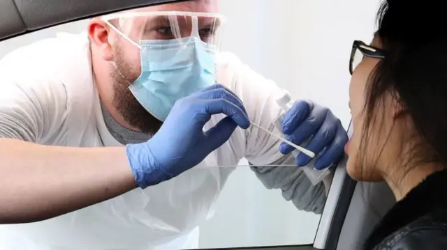 A woman being tested for coronavirus through a car window