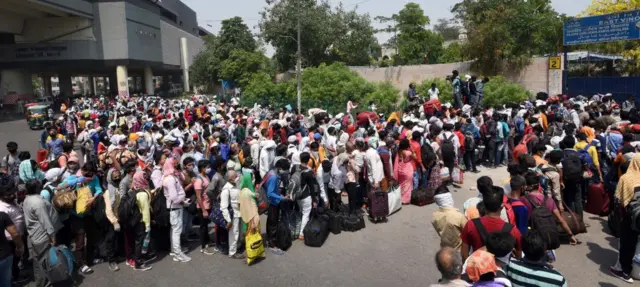 Migrants flouting social distancing wait to be screened at a Delhi Govt school in East Vinod Nagar before being taken by buses to railway stations from where they would board Shramik Special trains to their homes in other states on May 18, 2020 in New Delhi, India.