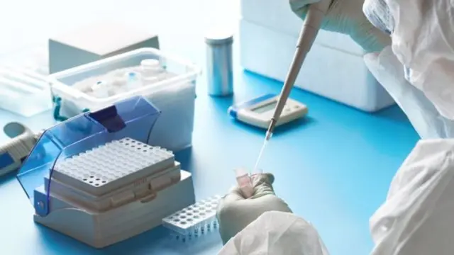 A scientist using a pipette on vials