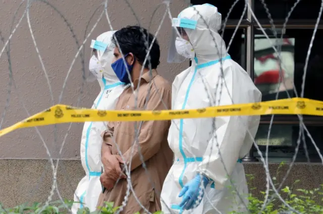 Police officers wearing protective suits pick up an illegal immigrant from an apartment under enhanced lockdown, during the movement control order due to the outbreak of the coronavirus disease (COVID-19), in Kuala Lumpur 01/05/2020 Reuters