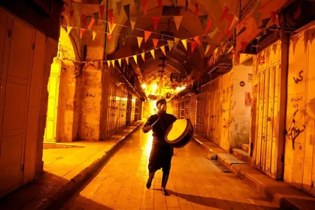 In Nablus in the West Bank, a man beats a drum to wake Muslims to have their pre-dawn meal