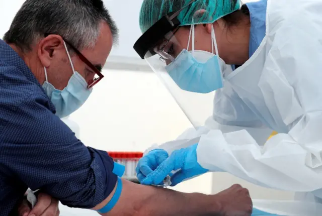 A paramedic takes a blood sample of a man for a COVID-19 antibodies test in Valencia, Spain