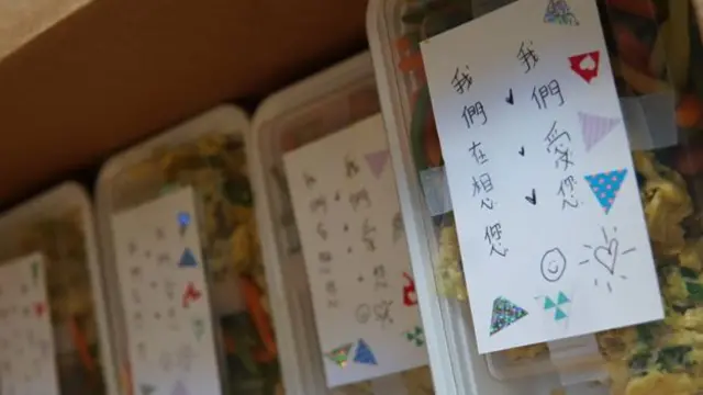 Handwritten notes in Chinese that say "we love you and are thinking of you", on top of food boxes