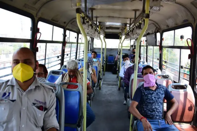 Passengers and a conductor using a Delhi Transport Corporation (DTC) bus while wearing face masks as a precaution, during the eased lockdown restrictions.