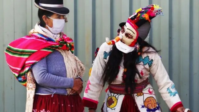 Person dressed as harlequin talking to a woman wearing a face mask