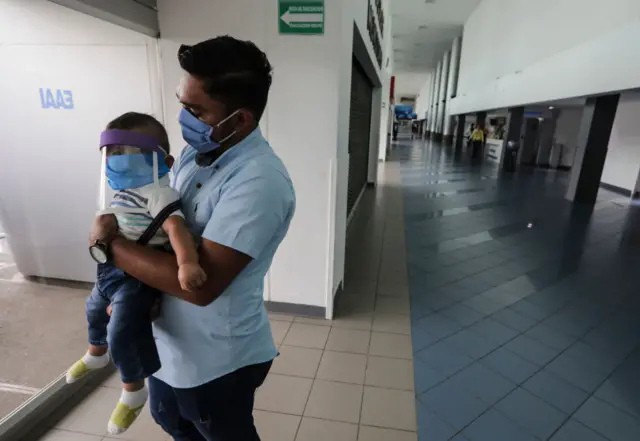 A US citizen holds his toddler while waiting to leave Nicaragua after the US embassy sent an alert encouraging its citizens to consider leaving the country due to the COVID-19 coronavirus pandemic, at the Augusto C. Sandino Airport in Managua on May 20, 2020