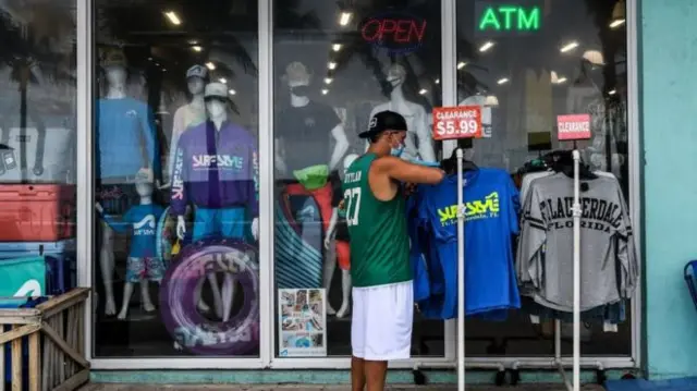 A man lining up shirts outside a shop