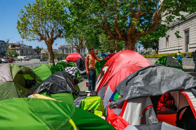 Jacob Corbin, 30, stands in a tent encampment on Fulton Street on Wednesday, May 6, 2020 in San Francisco, California.