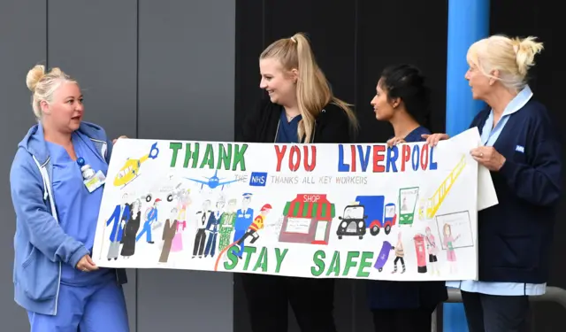 Health workers in Liverpool hold up a sign thanking Liverpool