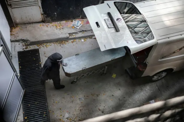 A mortuary worker moves the coffin with the remains of stretcher-bearer Hugo Lopez Camacho