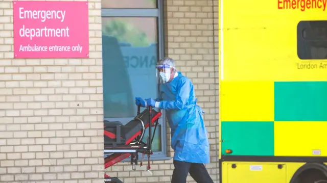 An NHS worker in PPE outside a hospital in England