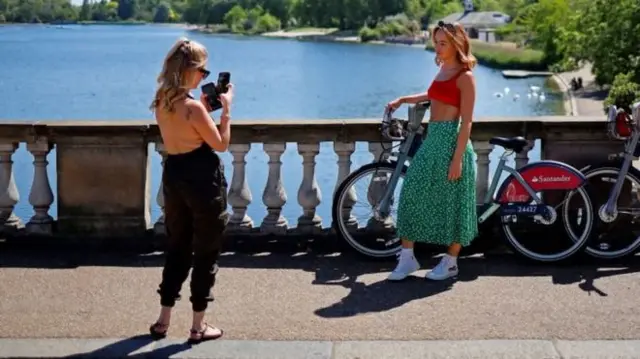 Two women meet in the park, one on a bike