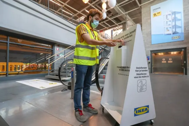 A German Ikea worker uses a hand sanitiser dispenser