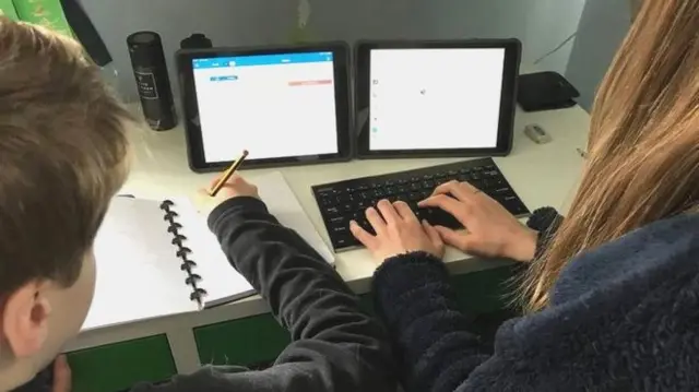 Pupils sit next to each other at a work station