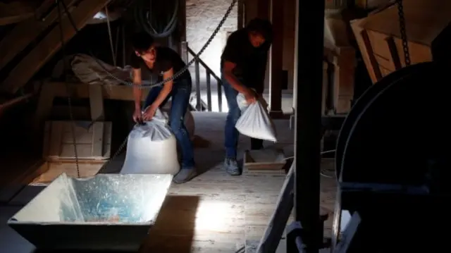 Miller Adrienne Delacroix (left) and a baker carry bags of spelt grains
