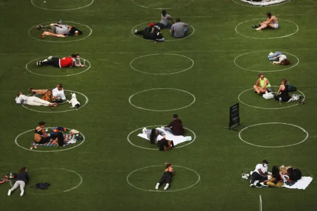 People sit in circles designed to encourage social distancing