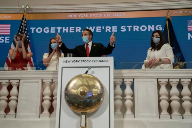 Cunningham (right) watches on as New York Gov Andrew Cuomo rings the market's bell earlier on Tuesday